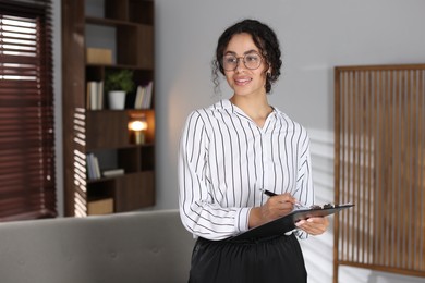 Photo of Professional psychologist with clipboard and pen in office, space for text