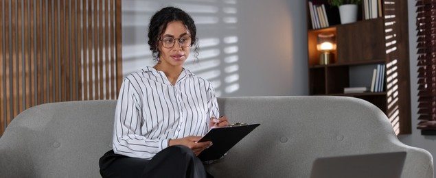 Photo of Professional psychologist with clipboard and pen in office