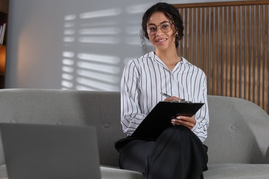 Photo of Professional psychologist with clipboard and pen in office
