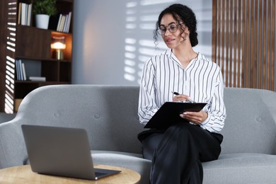 Photo of Professional psychologist taking notes while working with laptop in office
