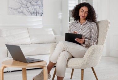 Photo of Professional psychologist taking notes while working with laptop in office