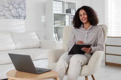 Photo of Professional psychologist with clipboard and pen in office