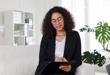 Photo of Professional psychologist with clipboard and pen in office