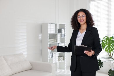 Photo of Professional psychologist with clipboard and pen in office, space for text