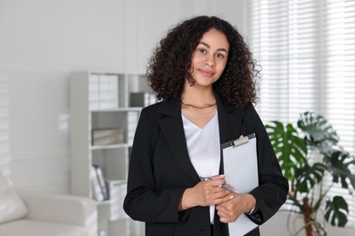 Photo of Professional psychologist with clipboard and pen in office