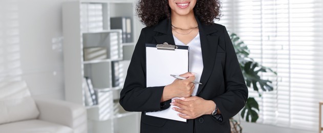 Photo of Professional psychologist with clipboard and pen in office, closeup