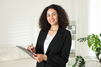 Photo of Professional psychologist with clipboard and pen in office