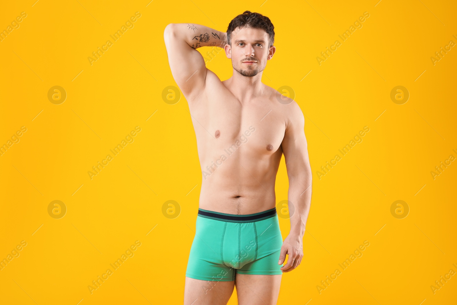 Young man in stylish turquoise underwear on orange background Photo of Young man in stylish turquoise underwear on orange background