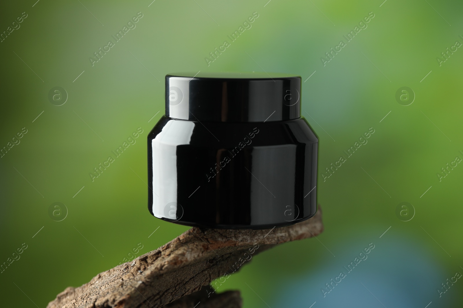 Jar of body cream on tree branch against blurred background, closeup Photo of Jar of body cream on tree branch against blurred background, closeup