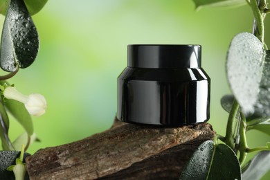 Photo of Jar of body cream on tree branch against blurred background, closeup