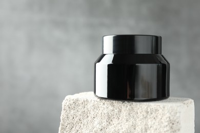 Photo of Jar of body cream on stone against grey background, closeup. Space for text