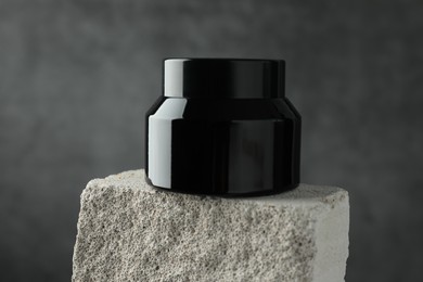 Photo of Jar of body cream on stone against grey background, closeup