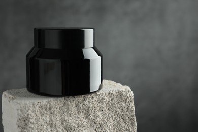 Photo of Jar of body cream on stone against grey background, closeup. Space for text
