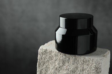 Photo of Jar of body cream on stone against grey background, closeup. Space for text
