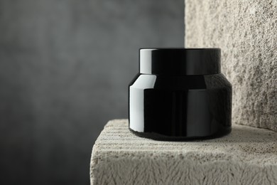 Photo of Jar of body cream on stone against grey background, closeup. Space for text