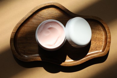 Photo of Jar of body cream on beige background, top view