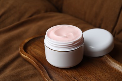 Photo of Jar of body cream on brown sofa, closeup