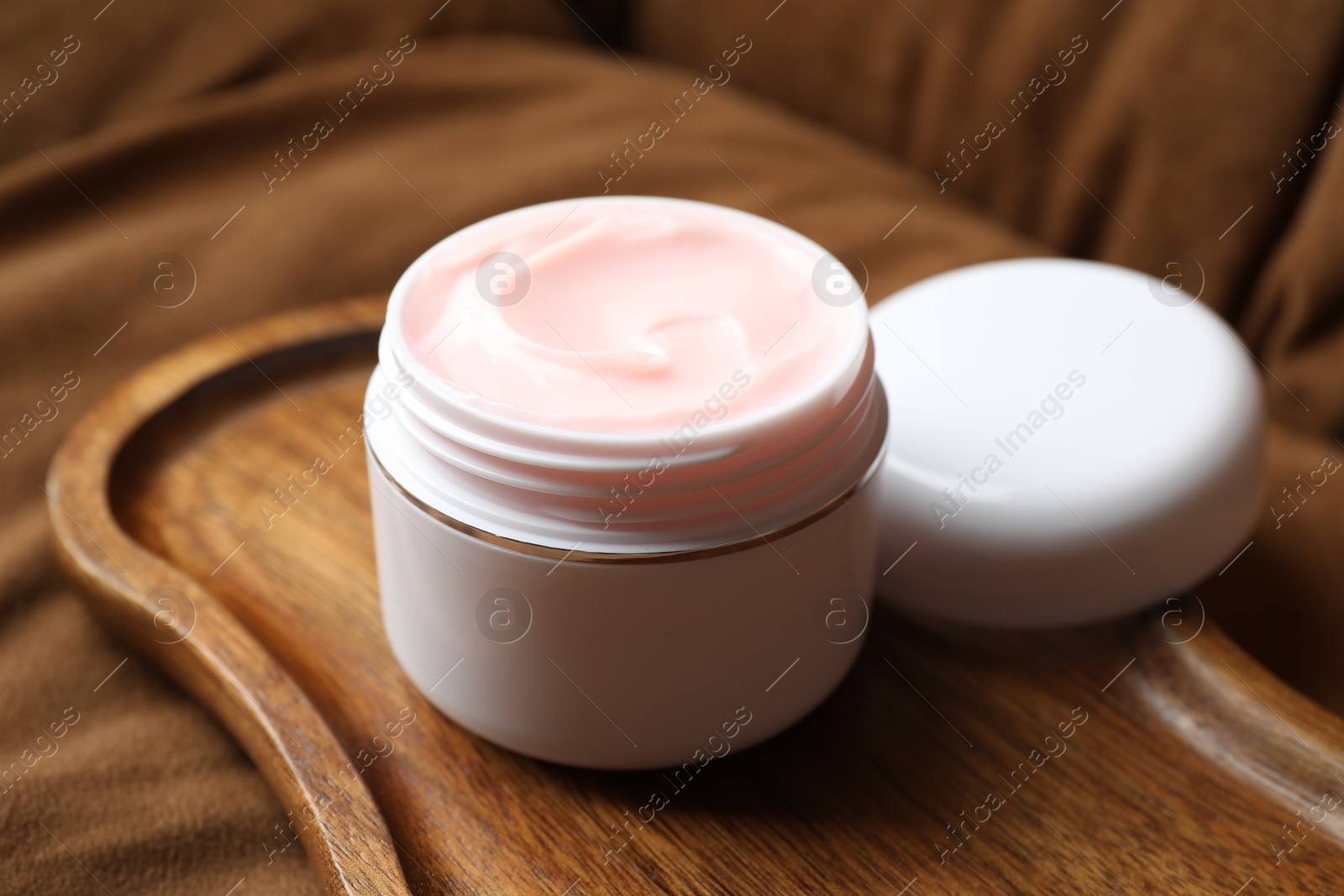 Jar of body cream on brown sofa, closeup Photo of Jar of body cream on brown sofa, closeup