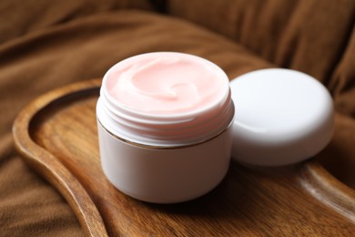 Photo of Jar of body cream on brown sofa, closeup