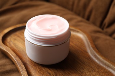 Photo of Jar of body cream on brown sofa, closeup