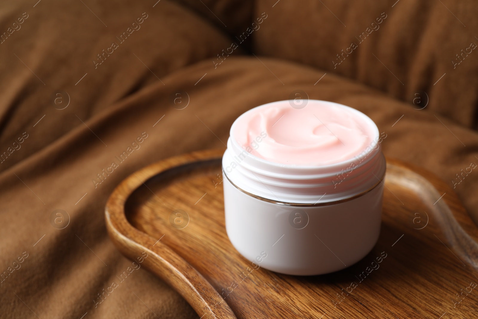 Jar of body cream on brown sofa, closeup Photo of Jar of body cream on brown sofa, closeup