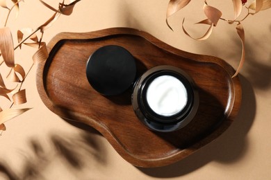 Photo of Jar of body cream and dry branches on beige background, flat lay