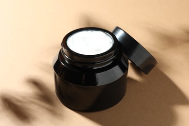 Photo of Jar of body cream on beige background, closeup