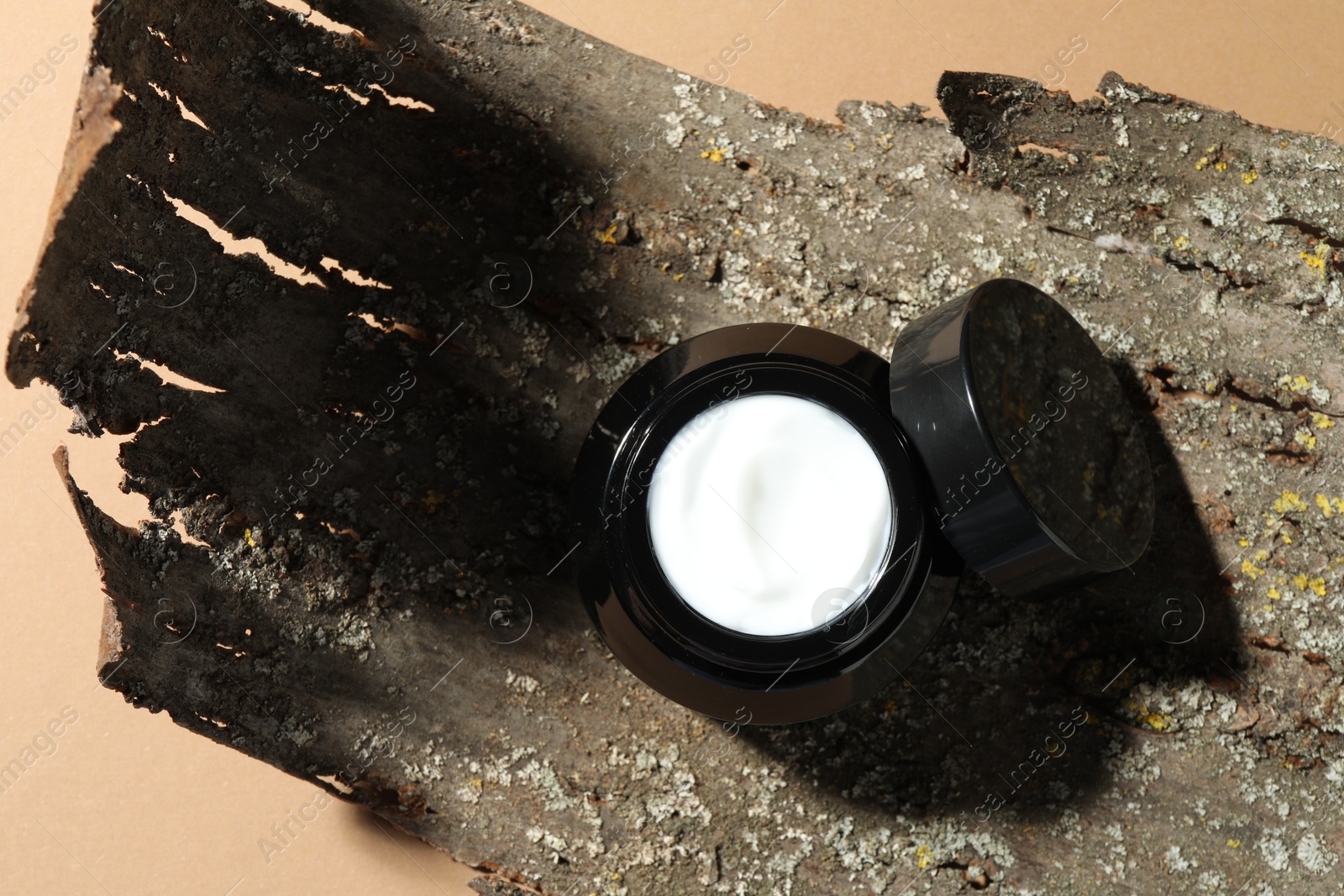 Jar of body cream and tree bark on beige background, top view Photo of Jar of body cream and tree bark on beige background, top view