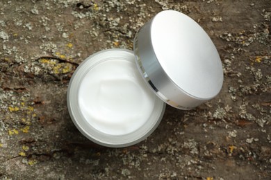 Photo of Jar of body cream on tree bark, top view