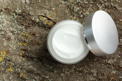 Photo of Jar of body cream on tree bark, top view. Space for text