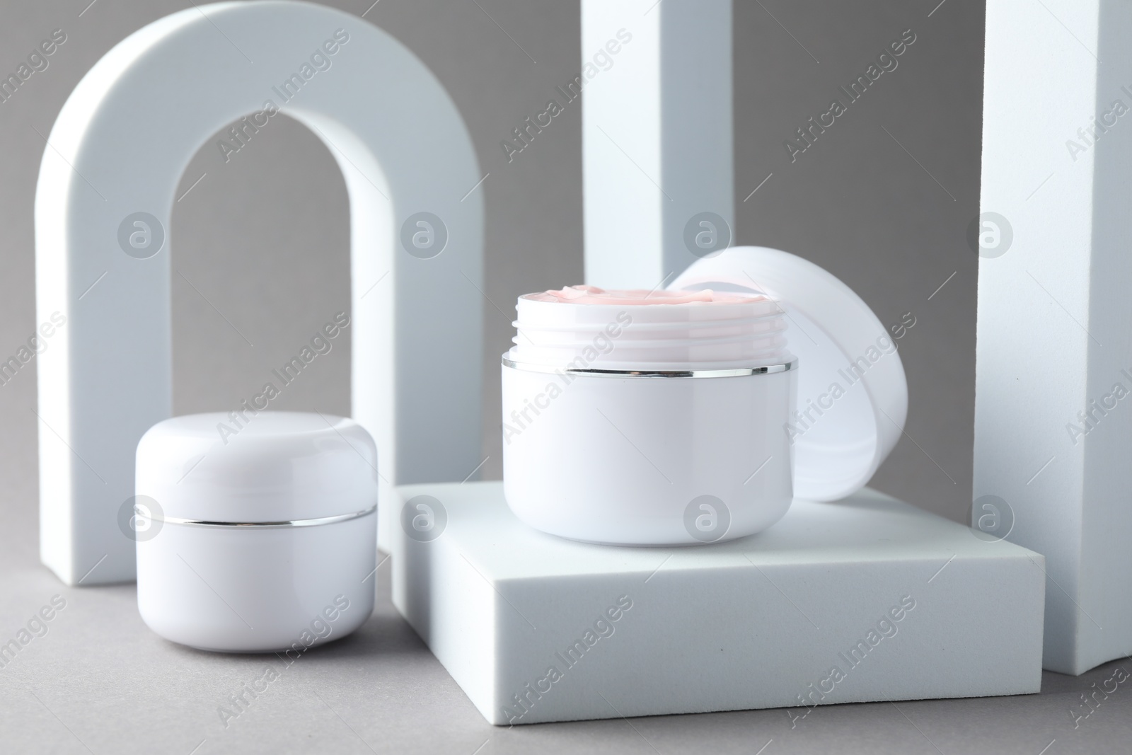 Stylish presentation of body cream in jars on light grey background, closeup Photo of Stylish presentation of body cream in jars on light grey background, closeup