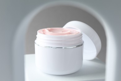 Photo of Stylish presentation of body cream in jar on light grey background, closeup