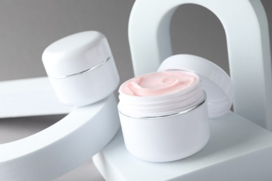 Photo of Stylish presentation of body cream in jars on light grey background, closeup