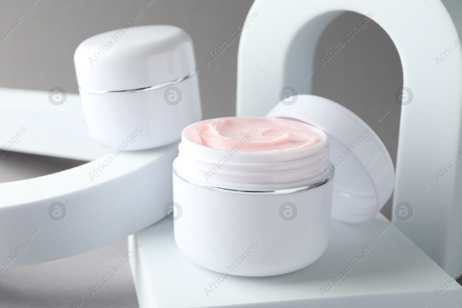 Stylish presentation of body cream in jars on light grey background, closeup Photo of Stylish presentation of body cream in jars on light grey background, closeup