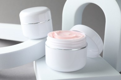 Photo of Stylish presentation of body cream in jars on light grey background, closeup