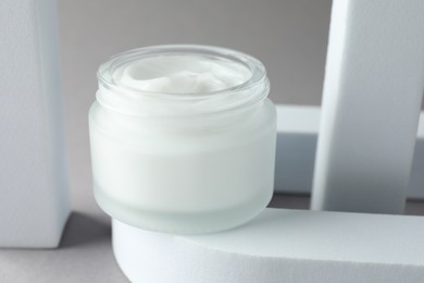 Photo of Stylish presentation of body cream in jar on light grey background, closeup