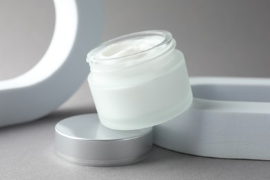 Photo of Stylish presentation of body cream in jar on light grey background, closeup