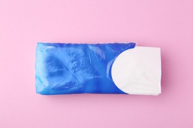 Photo of Paper handkerchiefs in package on pink background, top view