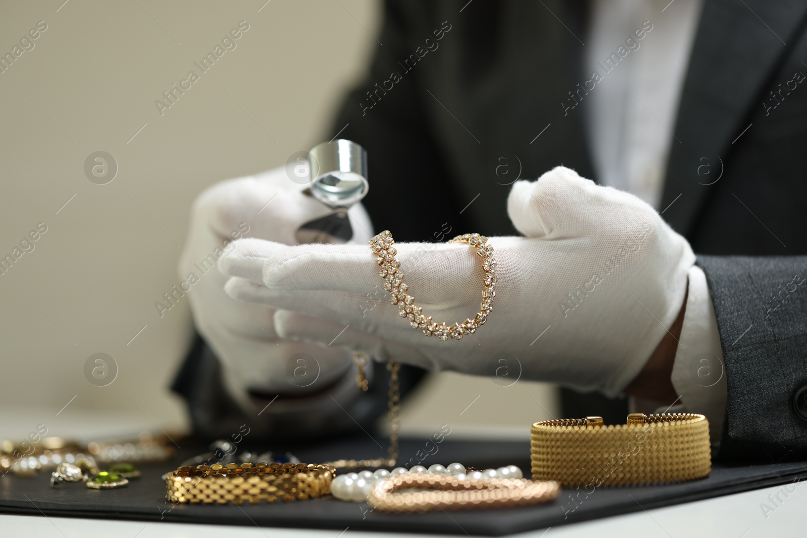 Appraiser evaluating luxury jewelry at table indoors, closeup Photo of Appraiser evaluating luxury jewelry at table indoors, closeup