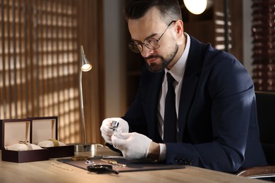 Photo of Appraiser with loupe evaluating ring at table indoors