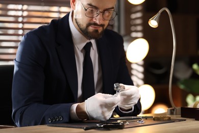Photo of Appraiser with loupe evaluating ring at table indoors