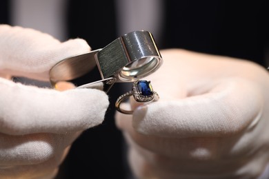Photo of Appraiser with loupe evaluating ring indoors, closeup