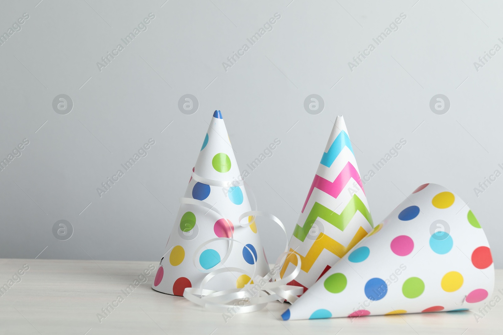 Party hats and festive decor on light background. Space for text Photo of Party hats and festive decor on light background. Space for text