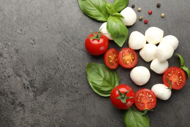 Photo of Mozzarella cheese, tomatoes, basil and peppercorns on grey table, flat lay. Space for text