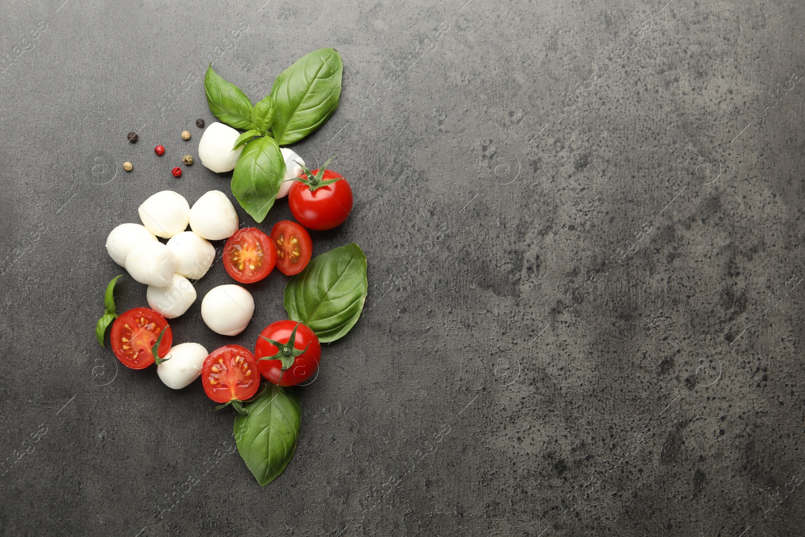 Mozzarella cheese, tomatoes, basil and peppercorns on grey table, flat lay. Space for text Photo of Mozzarella cheese, tomatoes, basil and peppercorns on grey table, flat lay. Space for text