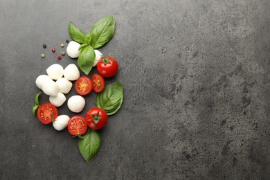 Photo of Mozzarella cheese, tomatoes, basil and peppercorns on grey table, flat lay. Space for text