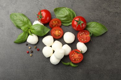 Photo of Mozzarella cheese, tomatoes, basil and peppercorns on grey table, flat lay