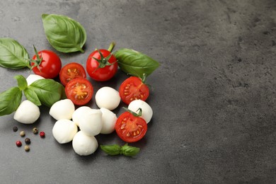 Photo of Mozzarella cheese, tomatoes, basil and peppercorns on grey table. Space for text