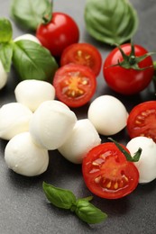 Photo of Mozzarella cheese, tomatoes and basil on grey table, closeup