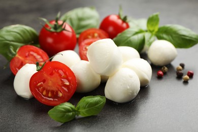 Photo of Mozzarella cheese, tomatoes, basil and peppercorns on grey table, closeup